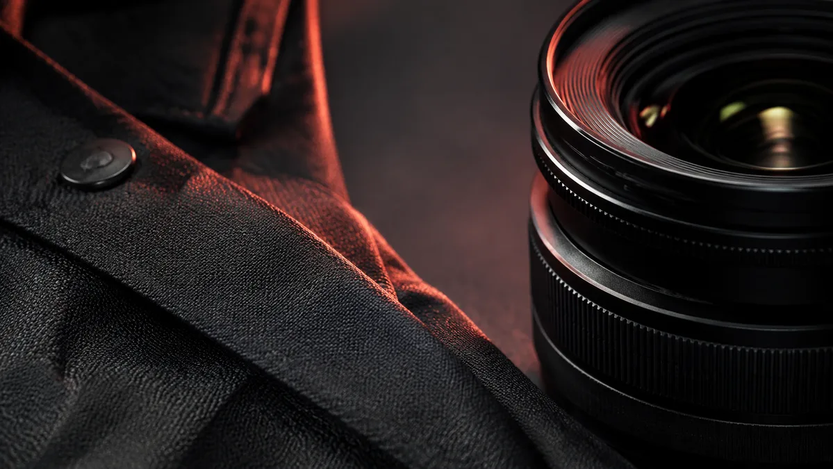 Fine woven fabric beside a camera lens in low light.
